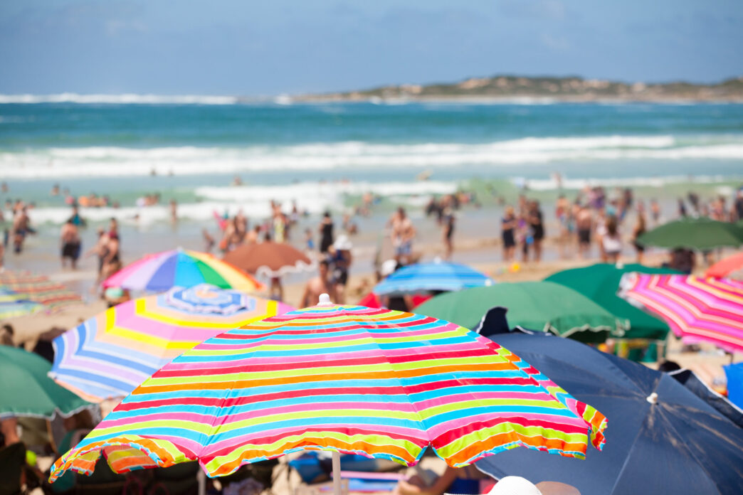 Beach scene with colorful umbrellas and people on the beach - Gringo Gazette
