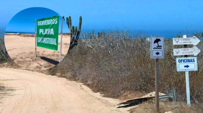 Beach entrance with a green sign reading 'Bienvenidos Plaza San Cristobal' along a sandy path, cacti nearby and distant blue sea.