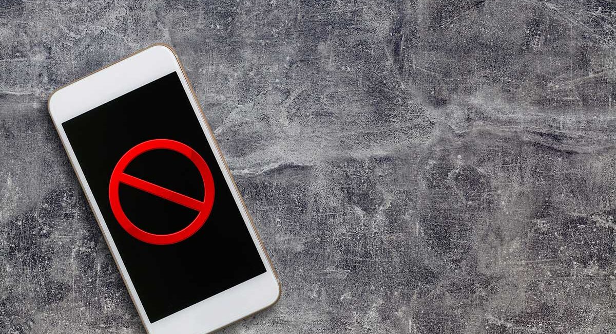 Smartphone on a rough gray surface displaying a red prohibition (no) symbol on the screen