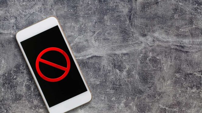 Smartphone on a rough gray surface displaying a red prohibition (no) symbol on the screen