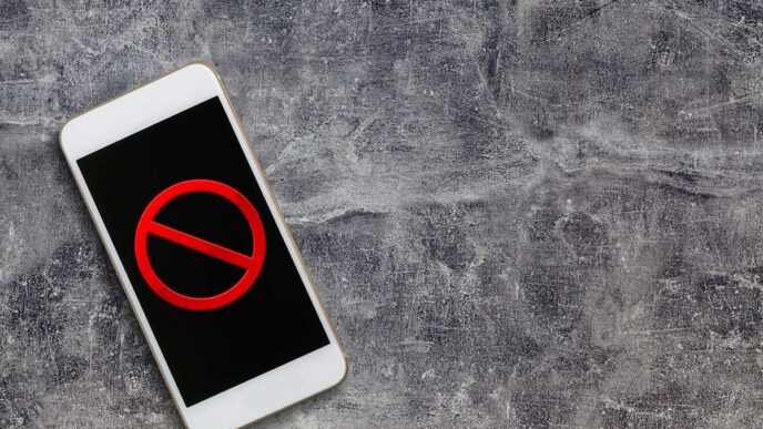Smartphone on a rough gray surface displaying a red prohibition (no) symbol on the screen