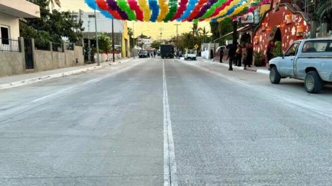 Colorful pennant banners stretched across a quiet urban street during a festival and sunset.