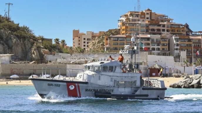 Rescue boat on calm blue water near a sandy beach with apartment buildings in the background