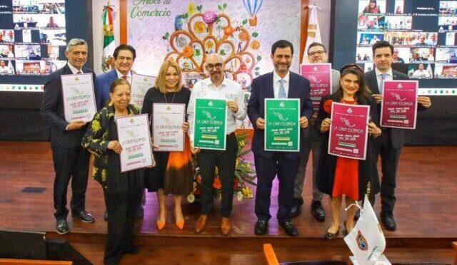 Ten people in business attire stand on a stage, each holding a certificate of achievement in different colors, with a decorative mural behind.