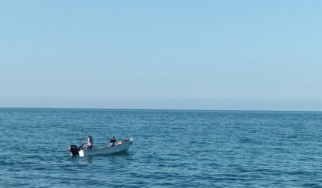 Agricultura-1 - Gringo Gazette Small motorboat with two people sailing on a calm blue sea under a clear sky.