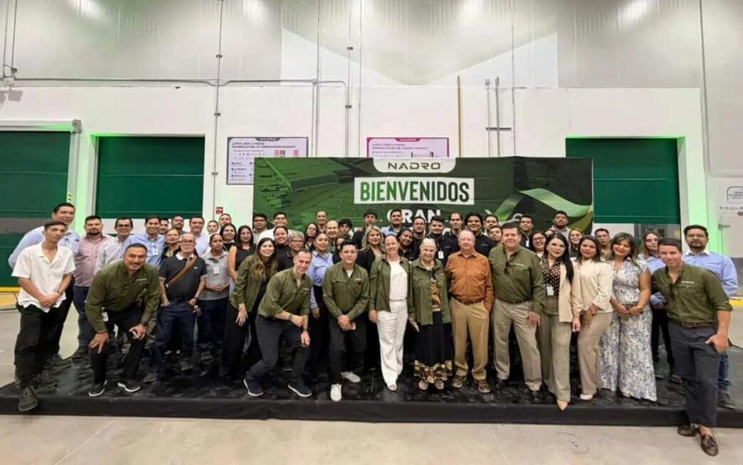 Group of people posing in a spacious industrial hall in front of a large Bienvenidos banner with Nadro logo behind them.