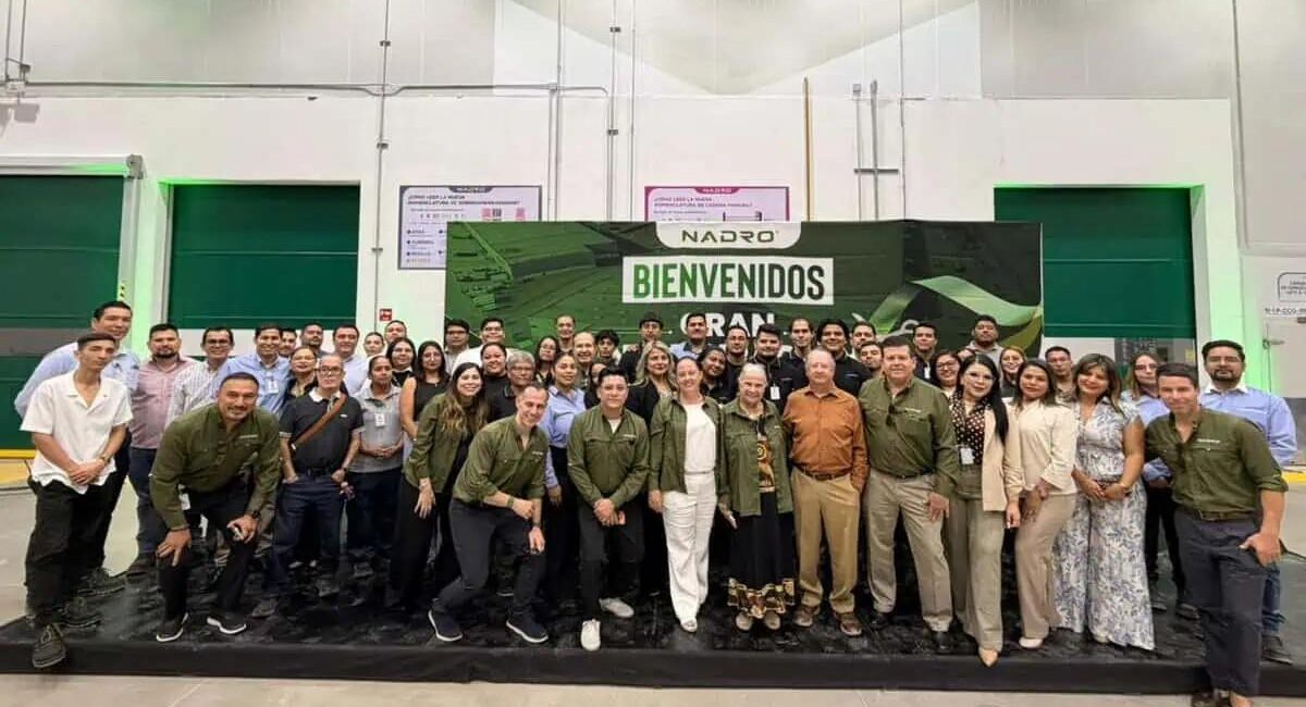 Group of people posing in a spacious industrial hall in front of a large Bienvenidos banner with Nadro logo behind them.