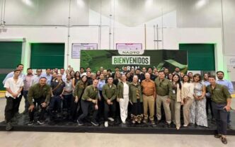 Group of people posing in a spacious industrial hall in front of a large Bienvenidos banner with Nadro logo behind them.