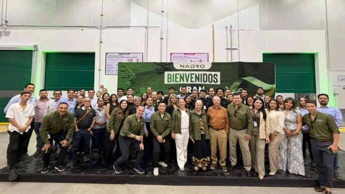 Group of people posing in a spacious industrial hall in front of a large Bienvenidos banner with Nadro logo behind them.