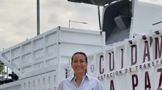 MayorQuiroga - Gringo Gazette Smiling woman standing in front of a large white industrial truck with a raised hopper at a transfer station