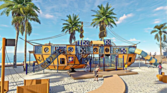 Colorful pirate ship–themed playground on a sandy beach with palm trees and a blue sky in the background.