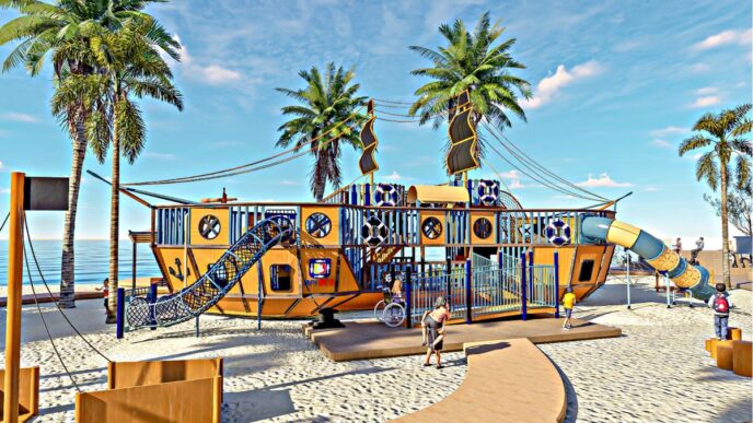 Colorful pirate ship–themed playground on a sandy beach with palm trees and a blue sky in the background.