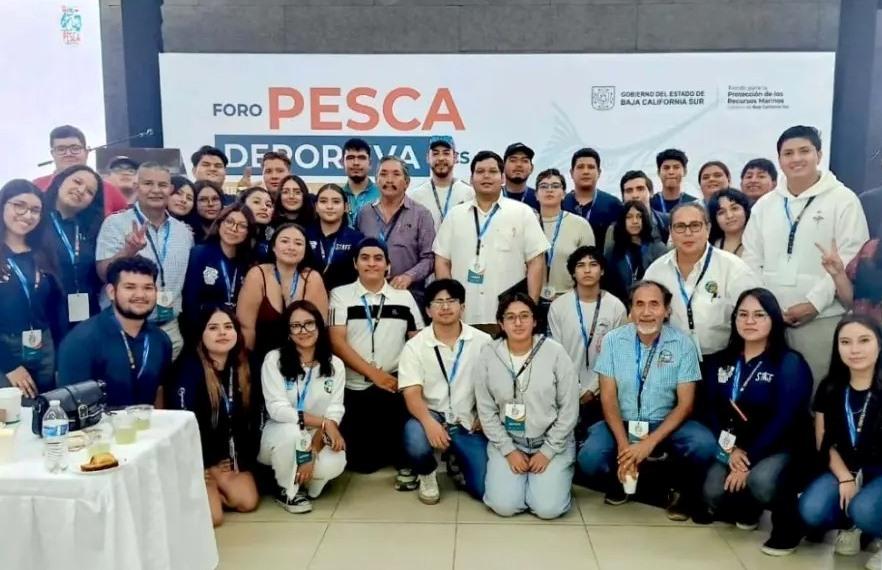 Large group of attendees posing for a photo at Foro Pesca Deportiva, wearing lanyards, with the event banner in the background.