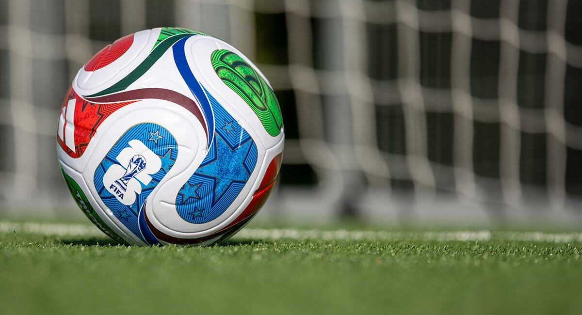 Colorful soccer ball on a green field with a blurred goal net in the background, marked with FIFA branding.