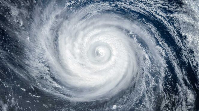 Satellite image of a powerful hurricane with a clearly defined eye and spiraling rain bands over the ocean.