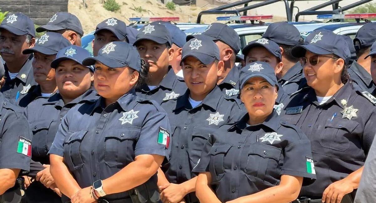 Group of Mexican police officers in dark gray uniforms and caps with star badges, standing together outdoors.