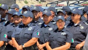 Group of Mexican police officers in dark gray uniforms and caps with star badges, standing together outdoors.