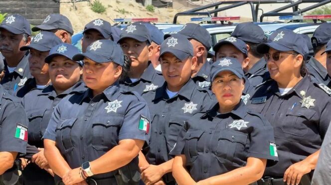 Group of Mexican police officers in dark gray uniforms and caps with star badges, standing together outdoors.