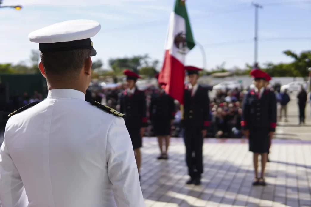 La Paz Names Navy Officer as New Police Chief - Gringo Gazette Back view of a white-dress military officer addressing a line of cadets at a ceremony, with a Mexican flag in the background.