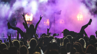 Silhouette of a crowd on a rock concert - Gringo Gazette Concert crowd with raised hands silhouetted against purple stage lights and smoke.