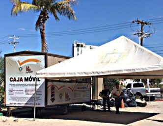 Mobile bank truck labeled Caja Móvil under a white canopy, with a palm tree and people nearby.