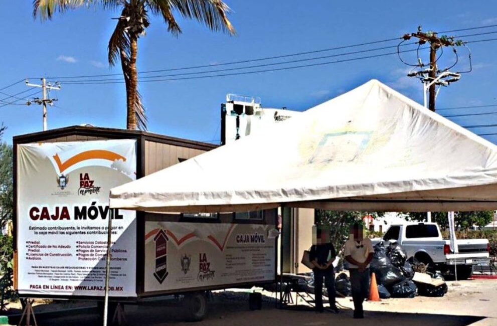 Mobile bank truck labeled Caja Móvil under a white canopy, with a palm tree and people nearby.
