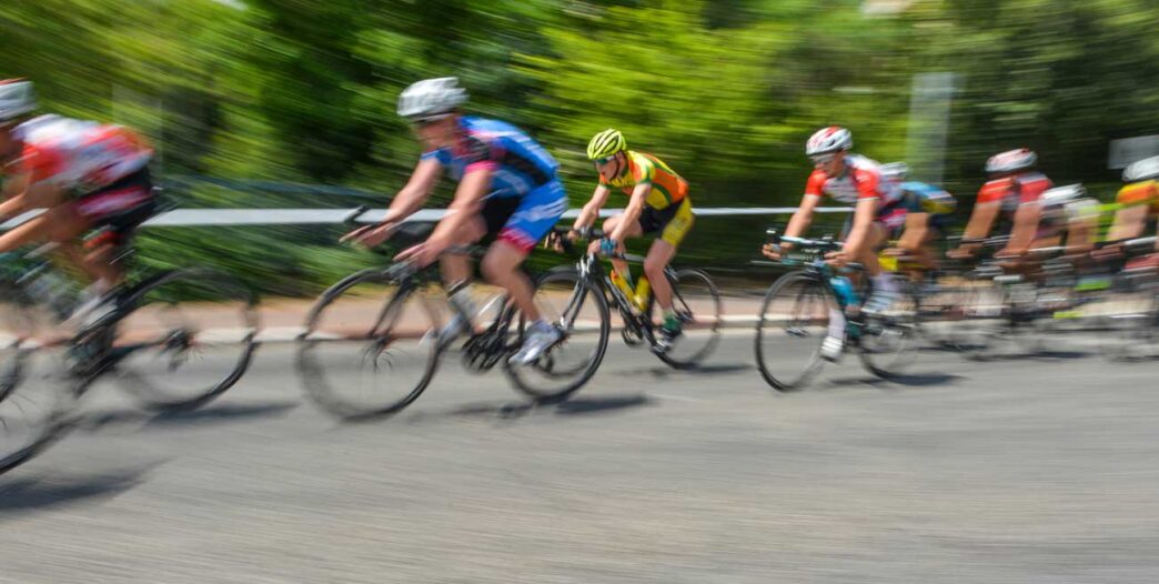tourFrance - Gringo Gazette Group of cyclists racing on a road, motion blur showing high speed and forward motion.