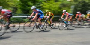 Group of cyclists racing on a road, motion blur showing high speed and forward motion.
