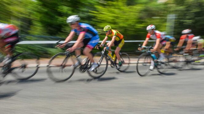 Group of cyclists racing on a road, motion blur showing high speed and forward motion.