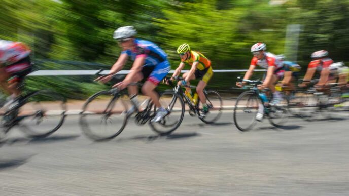 Group of cyclists racing on a road, motion blur showing high speed and forward motion.