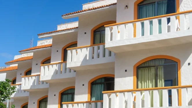 White Mediterranean-style apartment building with orange arches and balconies under a blue sky