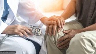 Doctor in a white coat holds a patient's hand, offering comfort and support during a check-up.