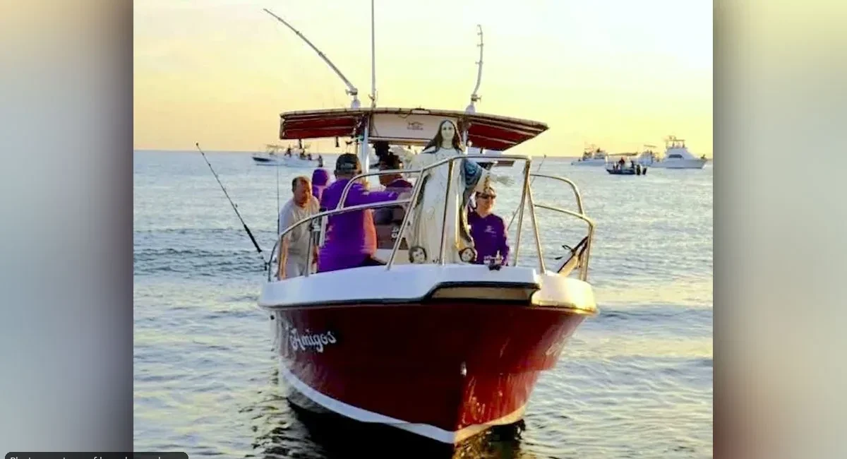 Group of people on a red boat fishing at sunset on calm water.