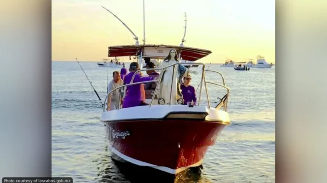 Group of people on a red boat fishing at sunset on calm water.