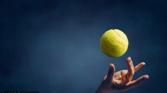 Tennis ball suspended midair above an open hand against a dark blue background