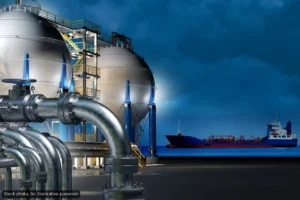Industrial facility with large spherical storage tanks and extensive piping beside a dock.