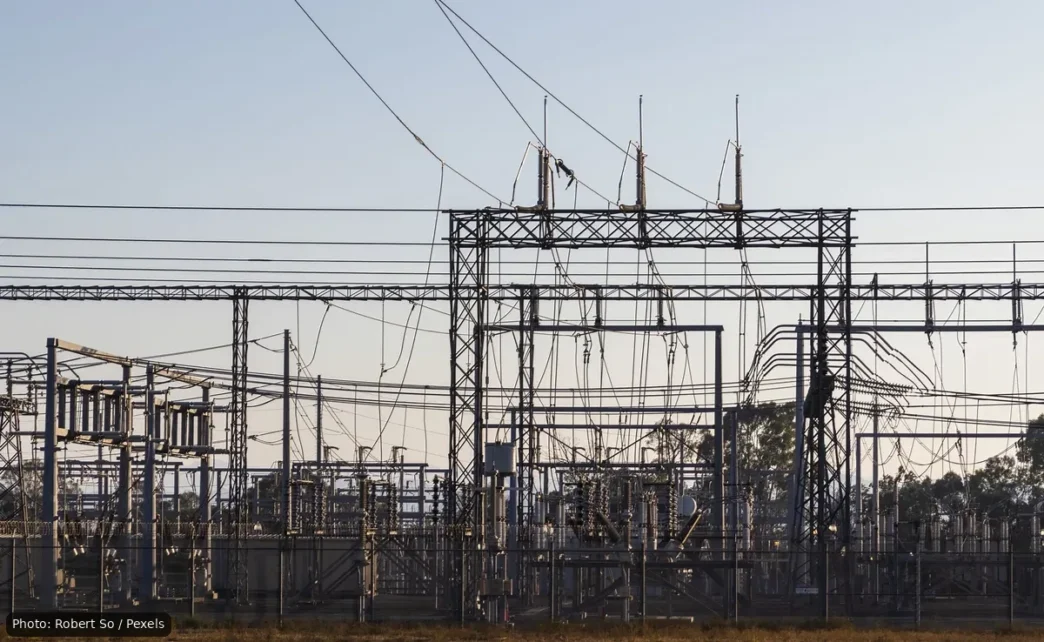 High-voltage electrical substation with metal lattice structures and a tangle of overhead power lines and insulators.