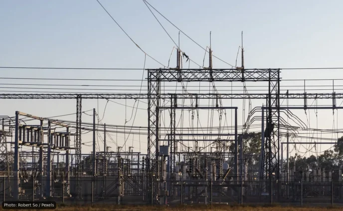 High-voltage electrical substation with metal lattice structures and a tangle of overhead power lines and insulators.