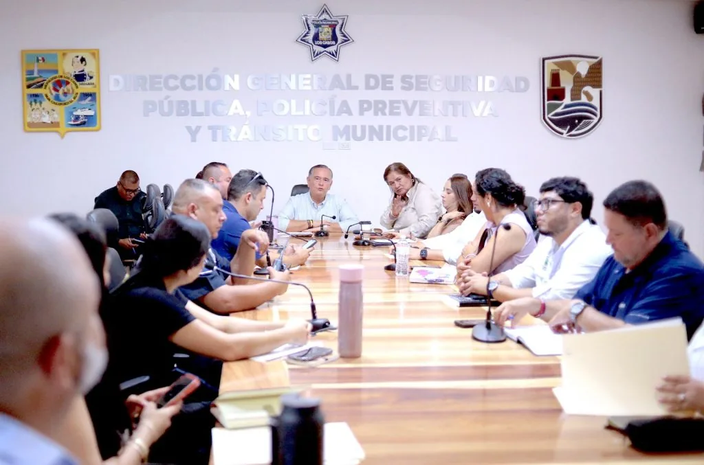Los Cabos Preps Independence Day Events Across Delegations - Gringo Gazette Group of officials seated around a long conference table in a police department briefing room, with emblems on the wall behind.