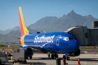 Southwest Airlines jet at gate with jet bridge attached, blue fuselage and mountainous desert backdrop