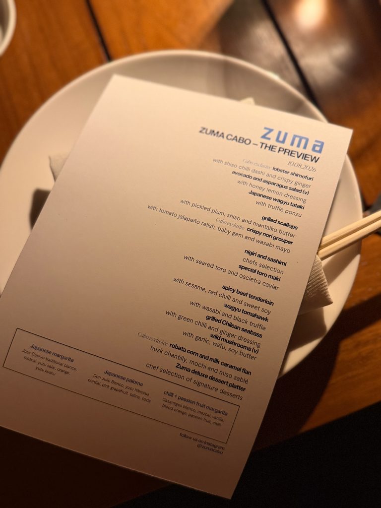 IMG_5539 - Gringo Gazette Menu resting on a white plate, featuring'ZUMA CABO—THE PREVIEW' at top and small dish text visible beneath.