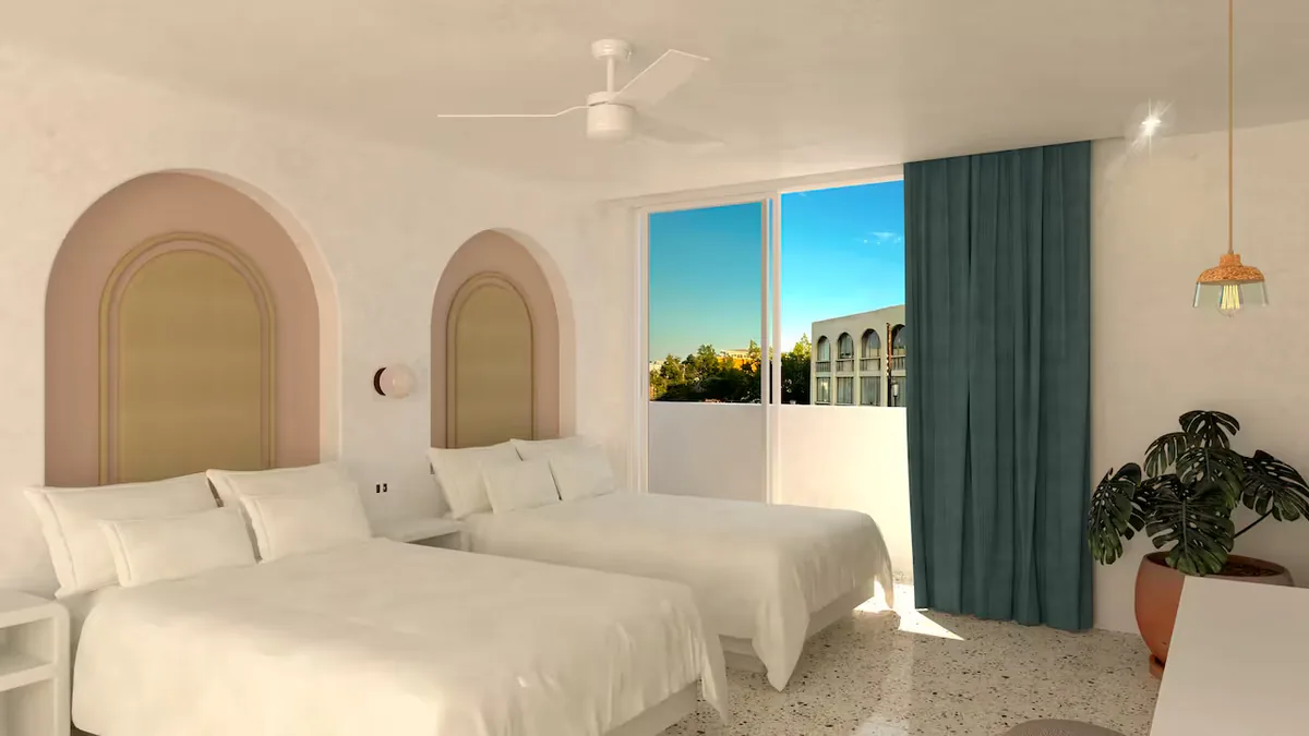 Hotel room with two white beds, curved padded headboards, terrazzo floor, and a balcony with blue curtains.